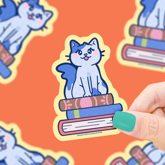Pegatina con forma de gato sentado sobre una pila de libros