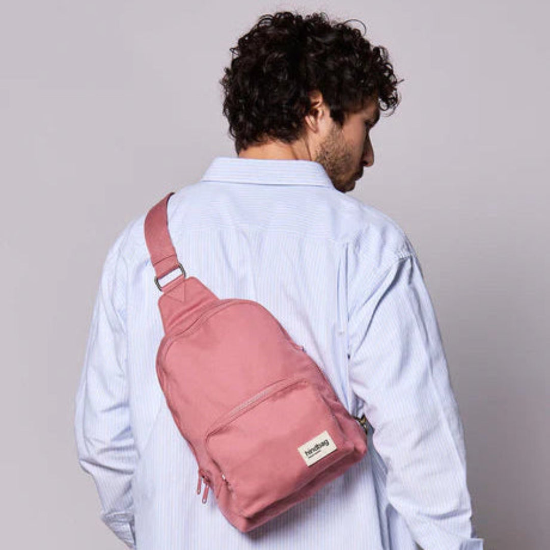 Chico con camisa y pelo rizado con un sling rosa de Hindbag a la espalda