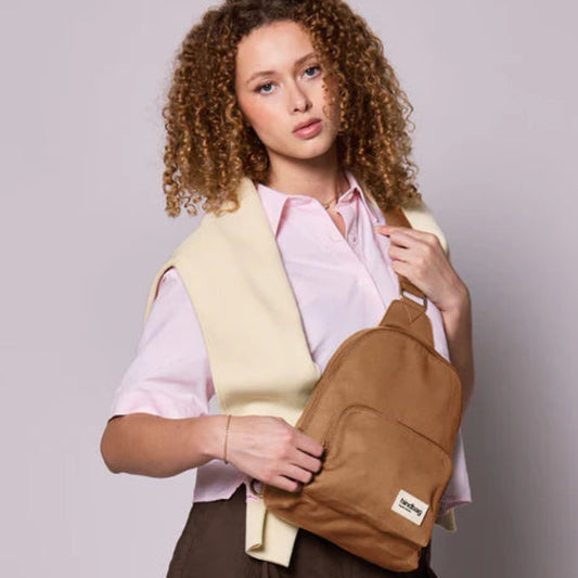 Mujer de pelo rizado con un sling color canela de hindbag
