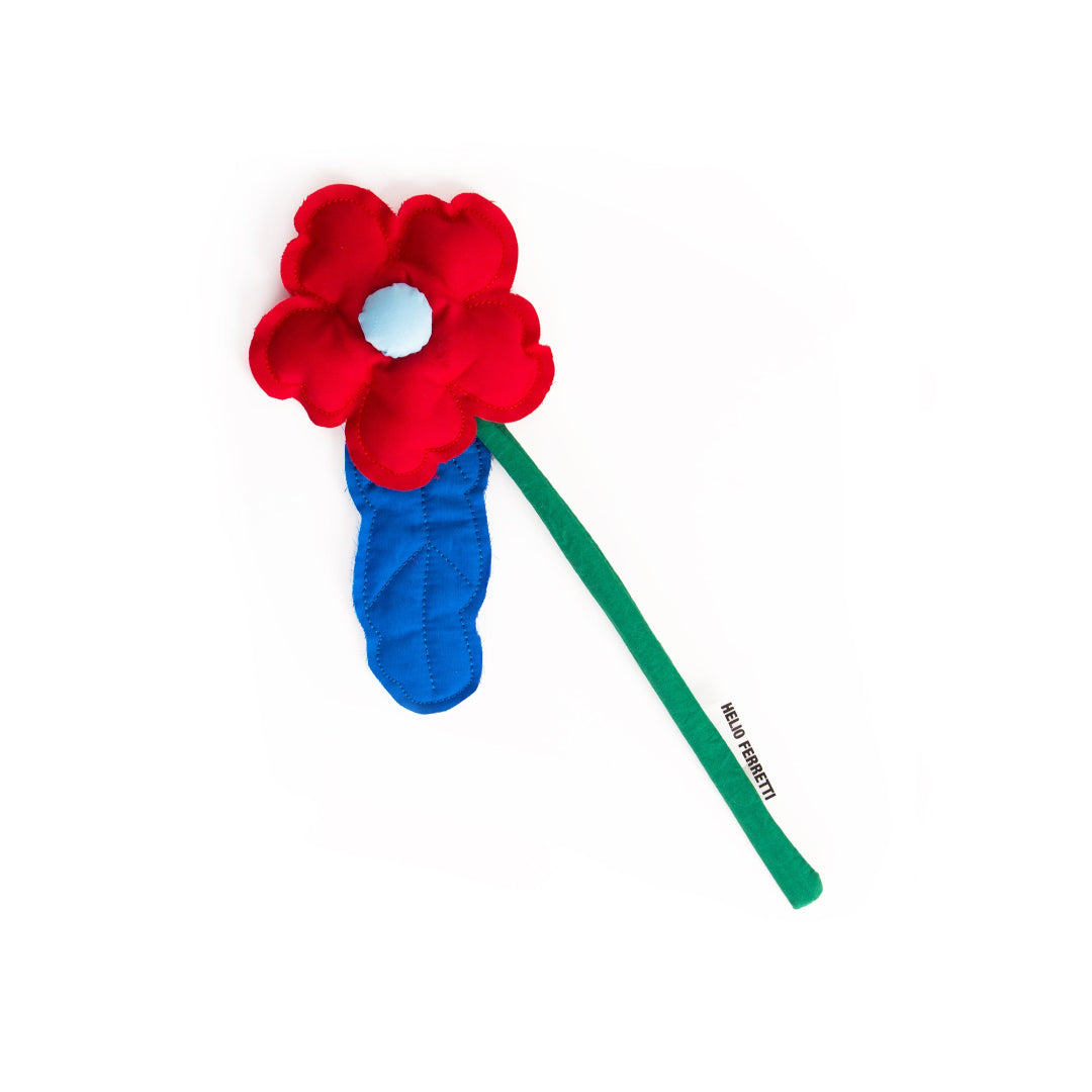 flor de tela decorativa de la marca Helio Ferretti en color rojo con el tallo verde y una hoja en azul