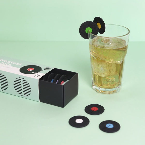 marcacopas en forma de discos de vinilo de colores enganchados sobre el borde de un vaso