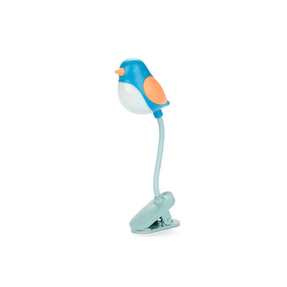 Luz de lectura azul en forma de pájaro enganchado a un libro sobre fondo blanco. 