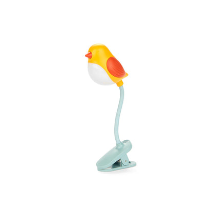 Luz de lectura amarilla en forma de pájaro enganchado a un libro sobre fondo blanco. 