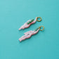 pendientes de metacrilato con aro dorado de la artista mitumi con dos mujeres nadando desnudas en color rosa con el pelo verde, sobre fondo azul