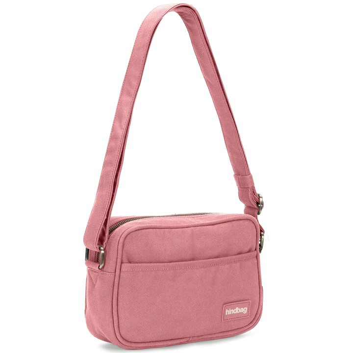 Vista en perspectiva de la bandolera rosa Nino de Hindbag, con detalle del lateral, el bolsillo frontal y la cremallera superior.
