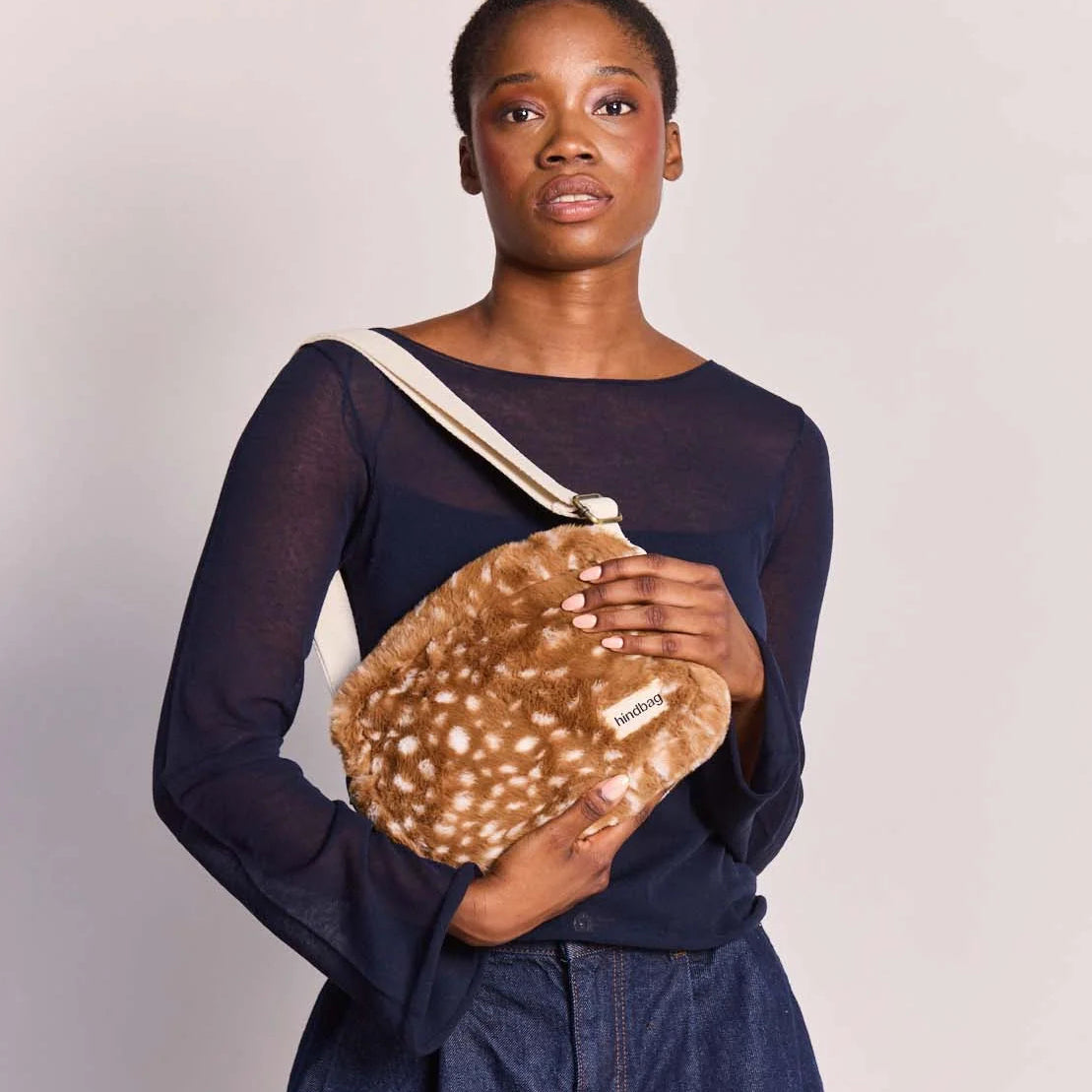 Modelo con bandolera Nino de Hindbag al hombro, de textura de pelo marrón con manchas claras de cervatillo y correa cruda.