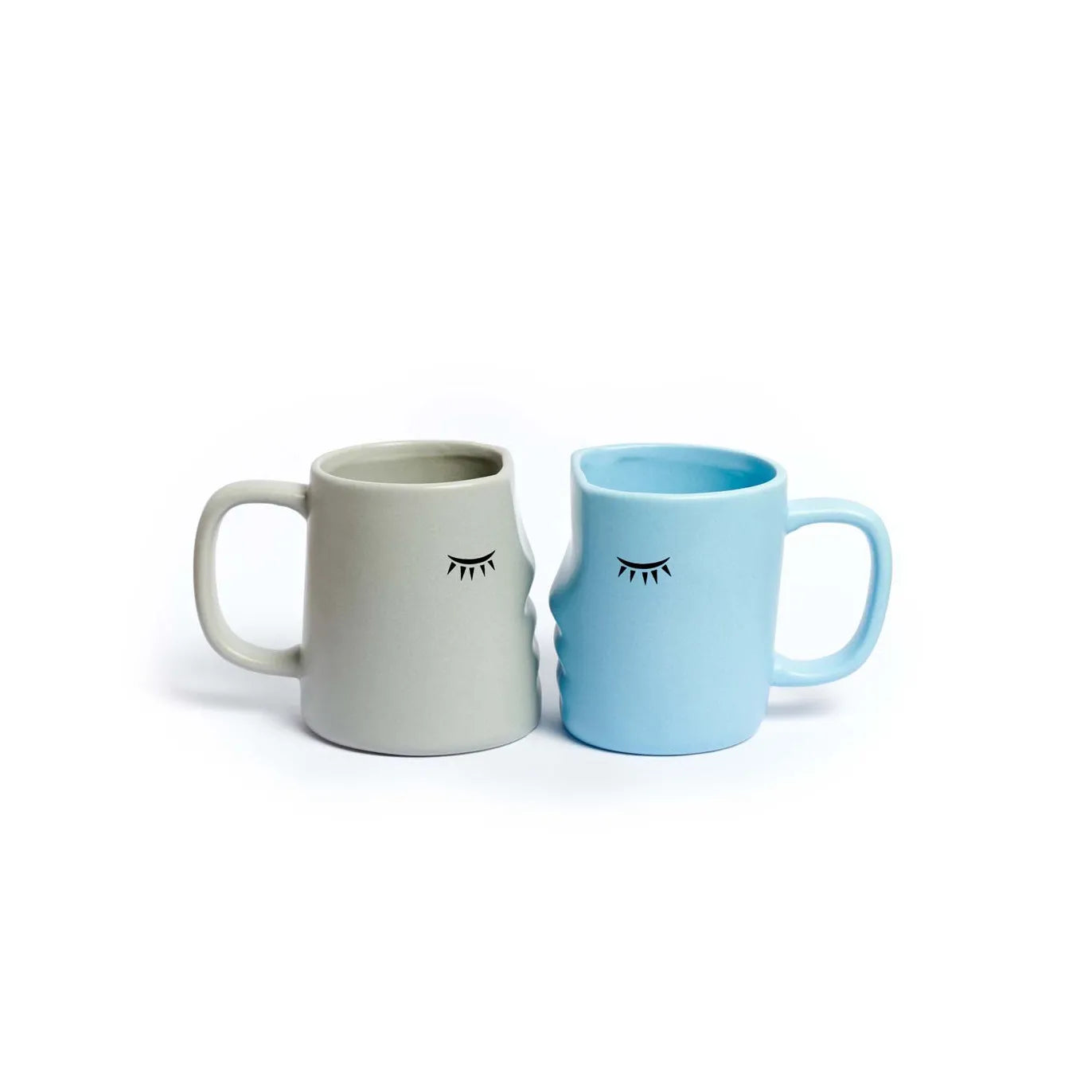 set de dos tazas en forma de caras de perfil que encajan dándose un beso con los ojos cerrados, una en color gris y otra en color azul