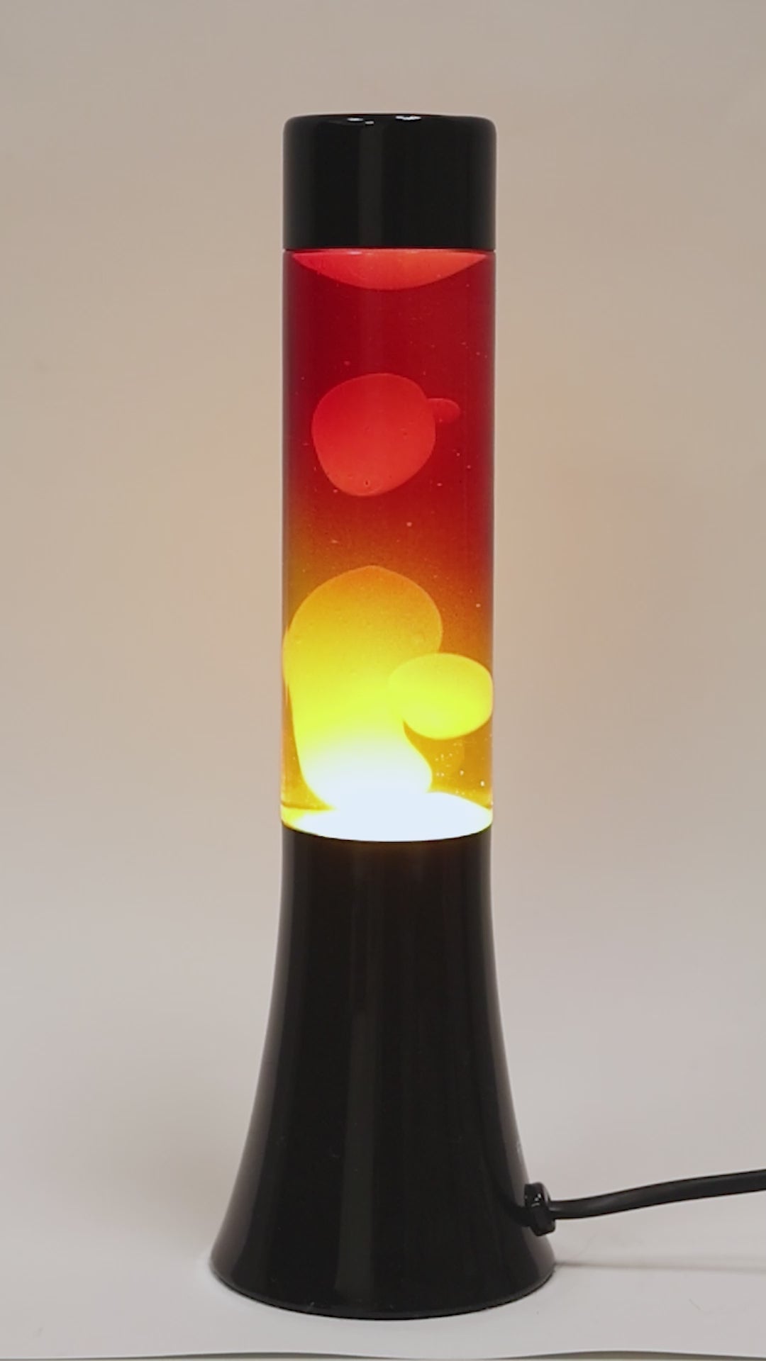 Lámpara lava con base cromada en negro y liquido amarillo y rojo