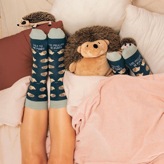 Calcetines azul marino con el texto solo tú me pones los pelillos de punta y erizos dibujados sobre una cama con erizos