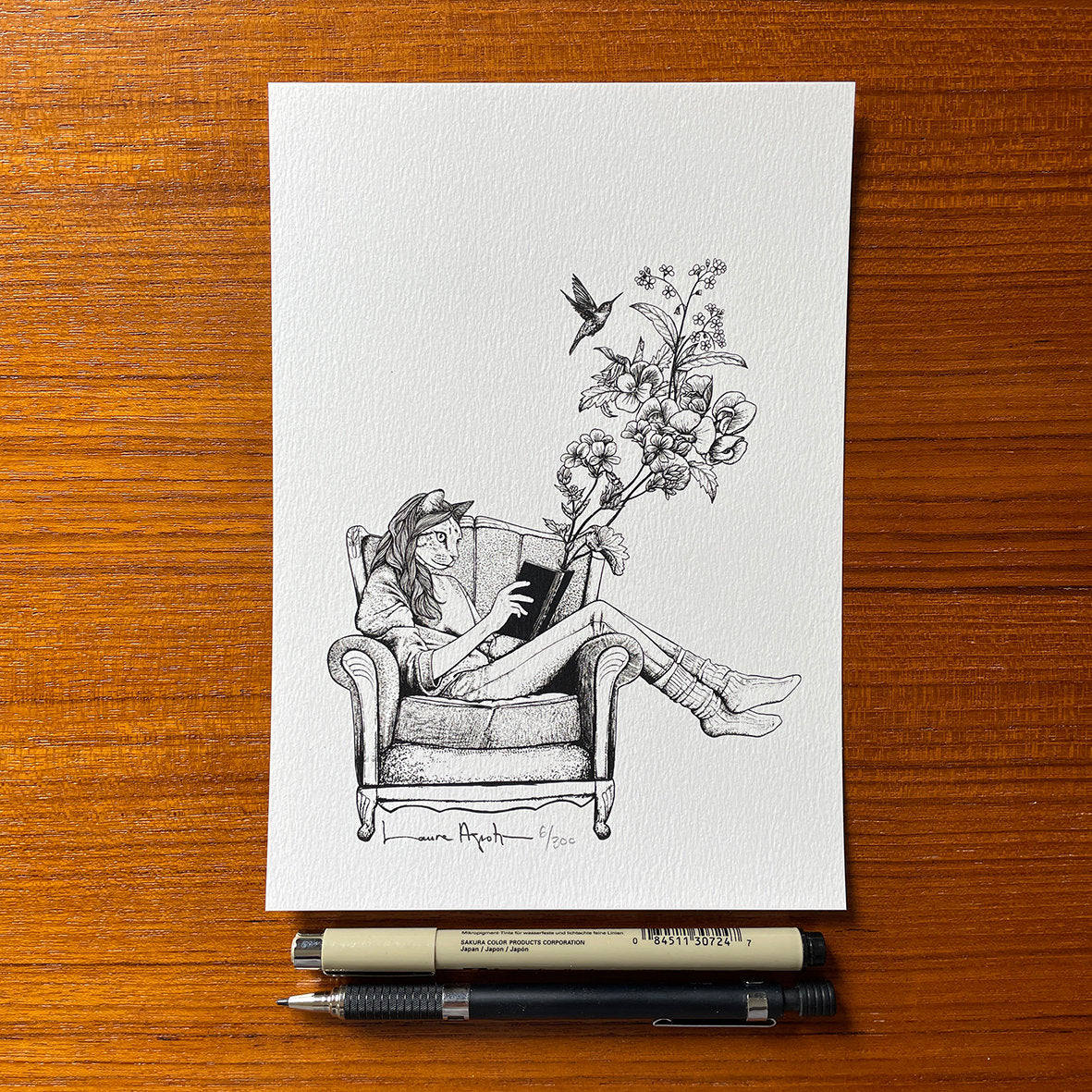 lámina impresa de Laura Agustí de una chica con cara de gato leyendo en un sofá