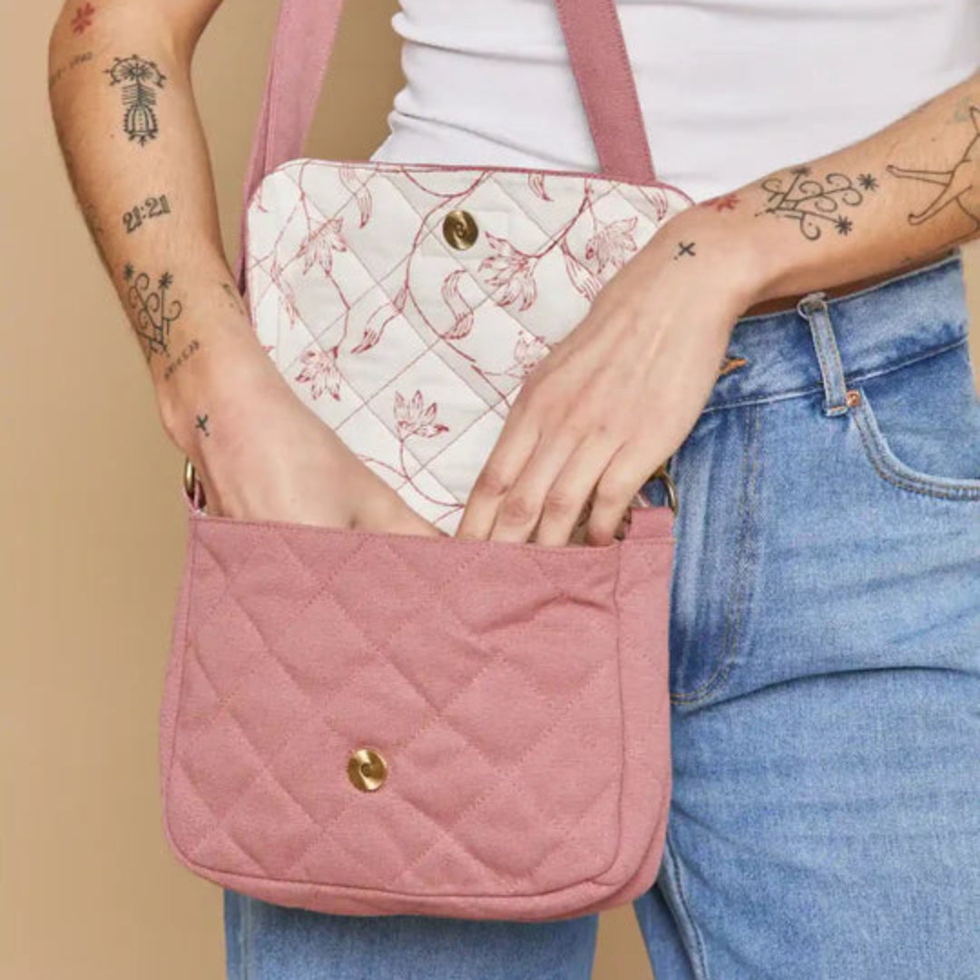 Mujer con el bolso acolchado pequeño en color rosa de la marca francesa Hindbag abierto con detalle de estampado floral en el interior de la solapa