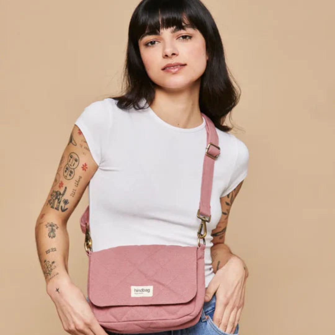 Mujer con camiseta blanca y tatuajes llevando el bolso acolchado pequeño en color rosa de la marca francesa Hindbag