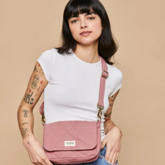 Mujer con camiseta blanca y tatuajes llevando el bolso acolchado pequeño en color rosa de la marca francesa Hindbag