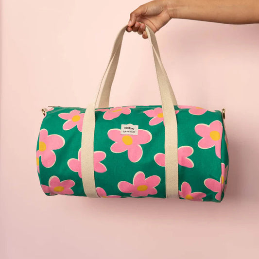 mano sujetanado la bolsa de viaje Simon de la marca Hindbag en colaboración con We are Jolies en color verde con patrón de flores rosas con el centro amarillo y las asas beige