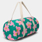 vista de medio lado de la bolsa de viaje Simon de la marca Hindbag en colaboración con We are Jolies en color verde con patrón de flores rosas con el centro amarillo y las asas beige