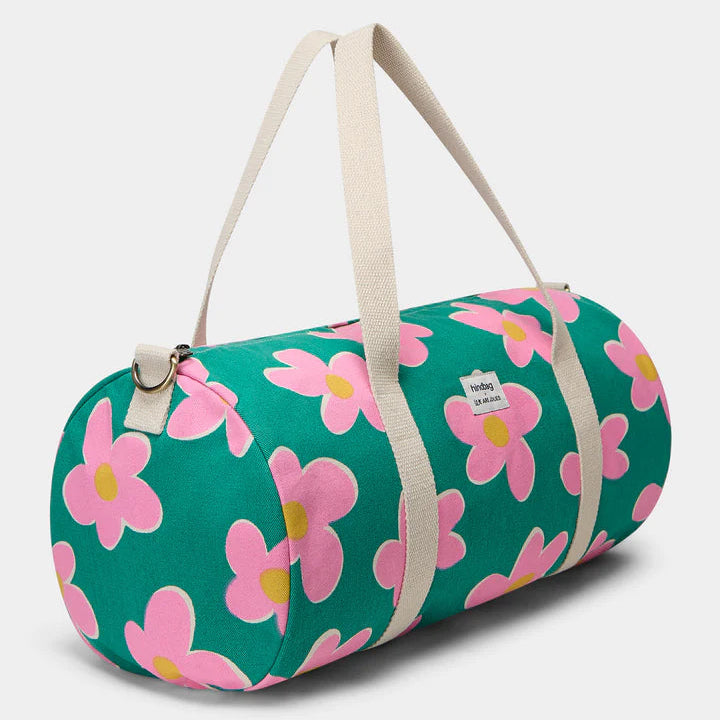 vista de medio lado de la bolsa de viaje Simon de la marca Hindbag en colaboración con We are Jolies en color verde con patrón de flores rosas con el centro amarillo y las asas beige