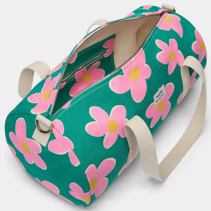 vista por dentro de la bolsa de viaje Simon de la marca Hindbag en colaboración con We are Jolies en color verde con patrón de flores rosas con el centro amarillo y las asas beige, con un bolsillo interior con el mismo patrón de flores y con cremallera