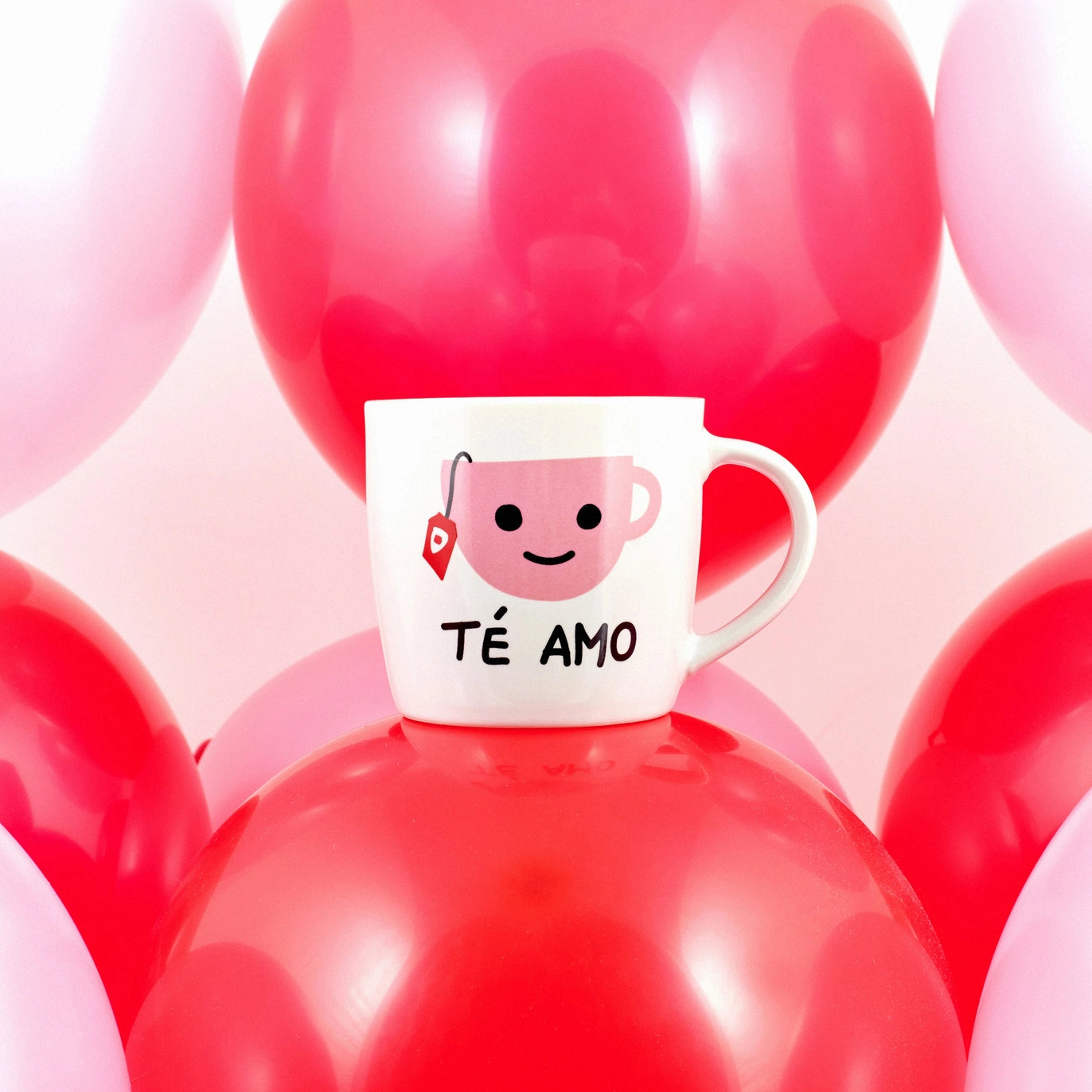 taza de porcelana con la imagen de una taza de té y la inscripción "té amo" con fondo de globos