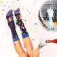 Mujer con zapatos de tacón transparente llenando una copa de champán junto a una bola de discoteca y los calcetines mágicos para que sea viernes