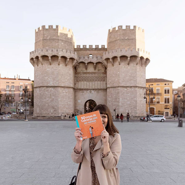 María Timor enseña su guía de lugares interesantes de Valencia delante de las Torres de Serrano