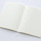 Cuaderno de papel japonés abierto con marcapáginas de seda blanca de hojas de cuadrícula tamaño A5