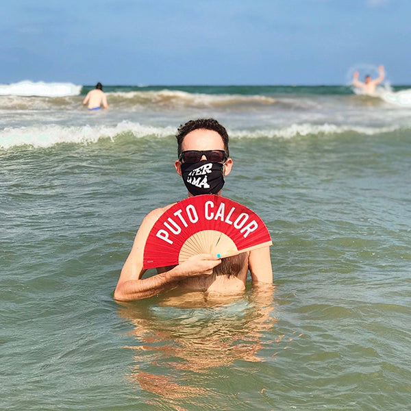 Hombre bañándose en el mar con una mascarilla y un abanico 