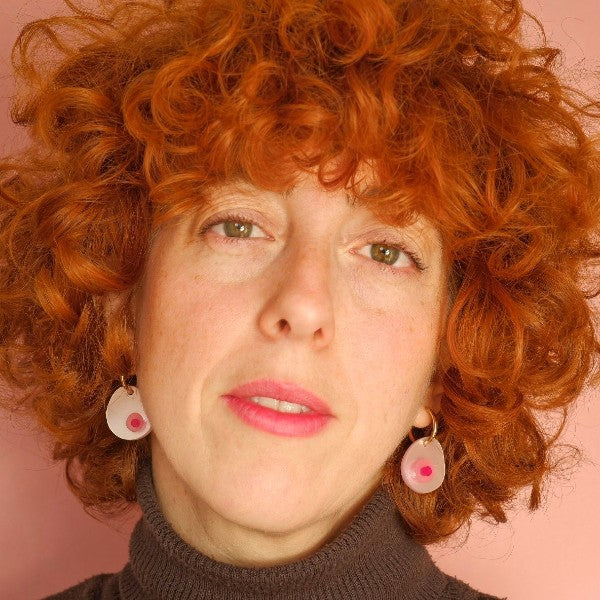 Mujer con el pelo rizado y rojo con los pendientes de aro Tetas rosas