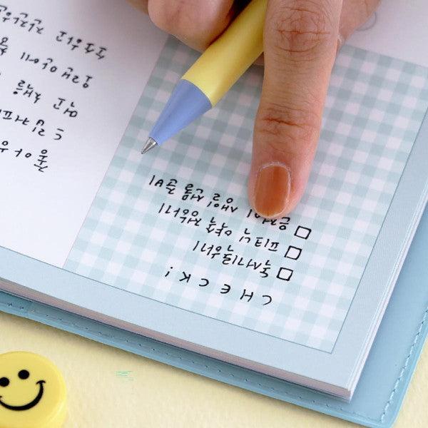 Una mano de mujer con el bolígrafo amarillo de Iconic señalando una checklist en un planner