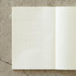 Hojas adhesivas con calendario en blanco pegado en un cuadernos Midori a cuadros