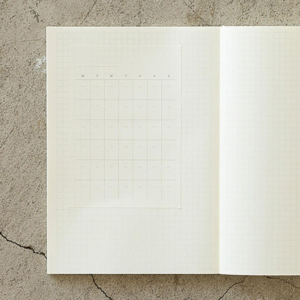 Hojas adhesivas con calendario en blanco pegado en un cuadernos Midori a cuadros