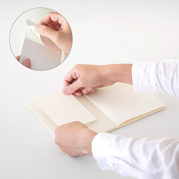 Persona pegando en un cuadernos Midori un calendario en blanco y detalle del adhesivo
