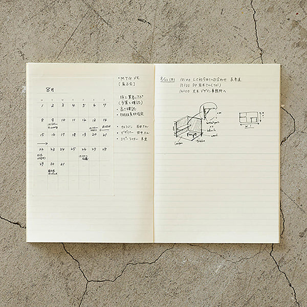 Cuaderno a rayas abierto con un calendario adhesivo en la hoja izquierda