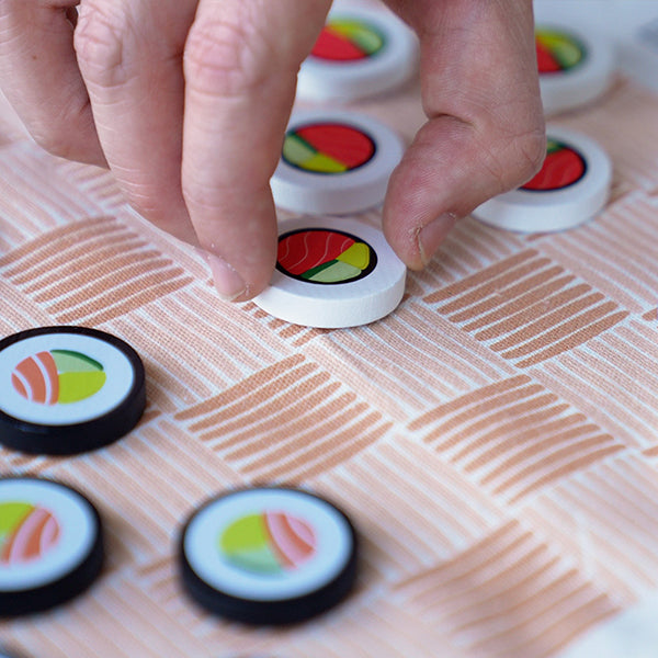 Juego de damas Damakis con piezas con forma de maki sushi y tablero enrollable de tela