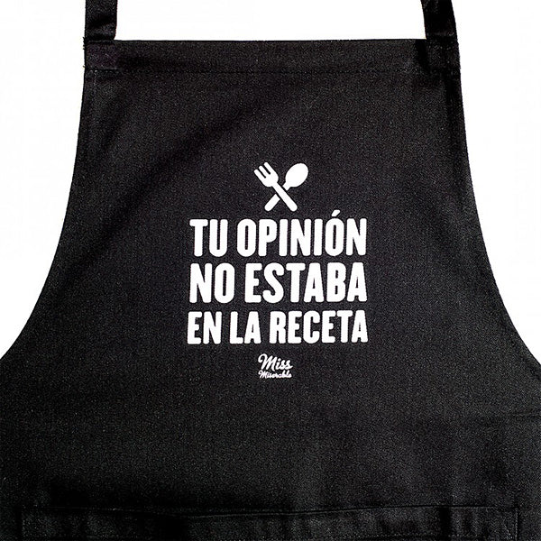 Primer plano del delantal de tela negro con bolsillo y el mensaje "Tu opinión no estaba en la receta" 