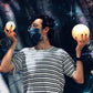 Hombre sujetando dos lámparas con forma de luna sobre fondo de graffitti de galaxia 