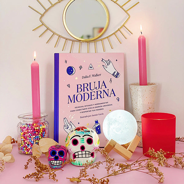 Libro de magia de la Bruja Moderna en un altar rodeado de objetos mágicos y esotéricos