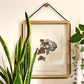 Marco de madera y cristal colgado en la pared con una ilustración de un cerebro con flores ilustrada por Laura Agustí