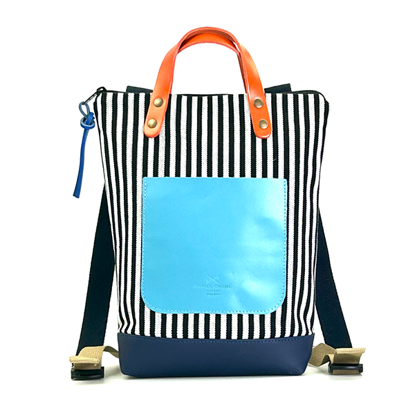 Mochila mini de lonera a rayas verticales blancas y negras y bolsillo central en cuero azul claro de Daniel Chong
