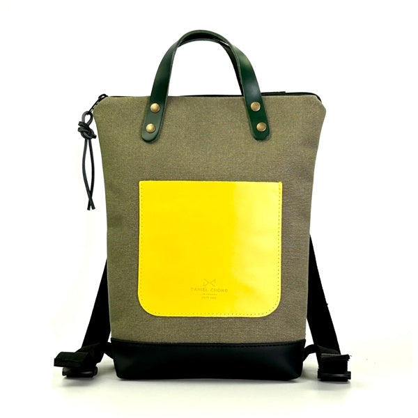 Mochila mini de loneta con bolsillo amarillo de cuero diseñada por Daniel Chong
