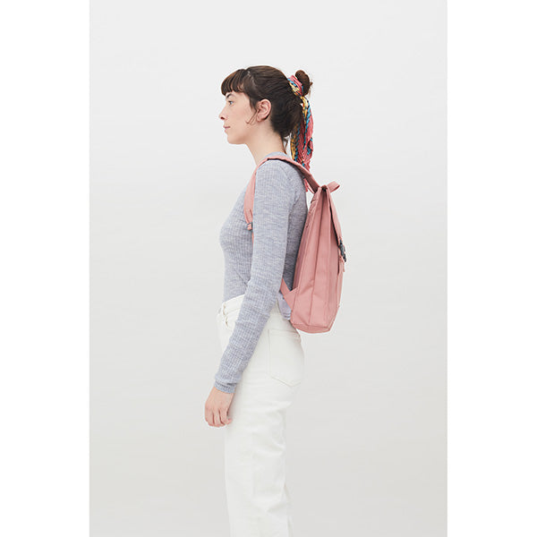 Mujer de perfil con una mochila rosa 100% reciclada con dos correas de la marca Lefrik