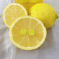 Pendientes con forma de limón enganchados en un limón partido por la mitad
