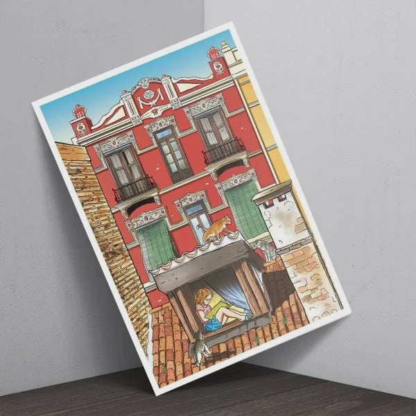 Postal de una fachada roja del Cabanyal con una chica sentada en una ventana leyendo y varios gatos por el tejado