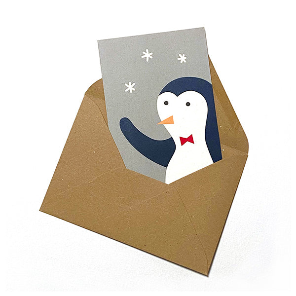Tarjeta de navidad con un pingüino saludando y sobre de papel craft ilustrada por Elisa Talens