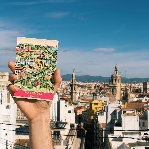 Mano sujetando una postal del centro histórico de Valencia con el Miguelete de fondo