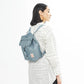 Mujer de tres cuartos con camisa blanca y la mochila pequeña reciclada azul claro de la marca lefrik