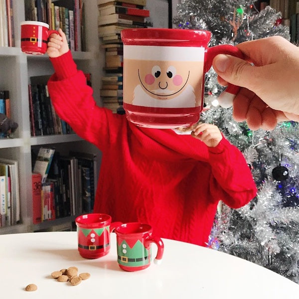 Mano sujetando una taza de color rojo con la cara de Papá Noel