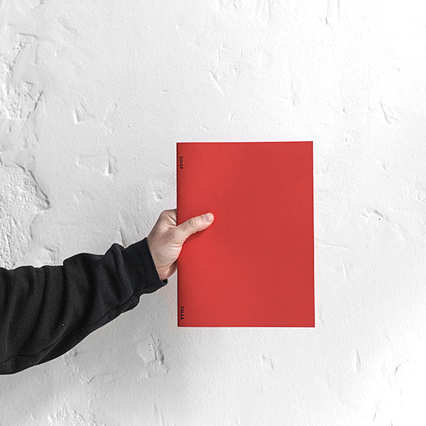 Una persona sostiene la libreta de Colla en tamaño A4, color rojo e interior liso