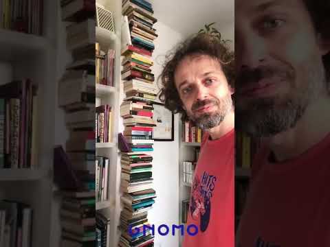 Un hombre enseña cómo funciona y cómo queda la estantería virtual en una habitación con muchos libros.