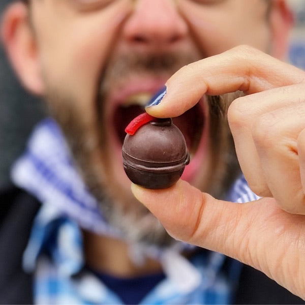 hombre a punto de comerse un bombón de chocolate relleno de cazalla, de la marca Utopick Cacao