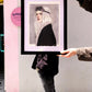 Una persona posa con un marco negro para fotos o prints con una lámina de Esther Gili